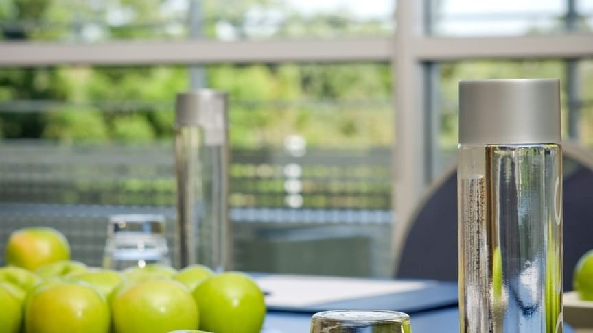 Conference table with green apples, glasses, and a water pitcher in Forest Room at Novotel Sydney Olympic Park