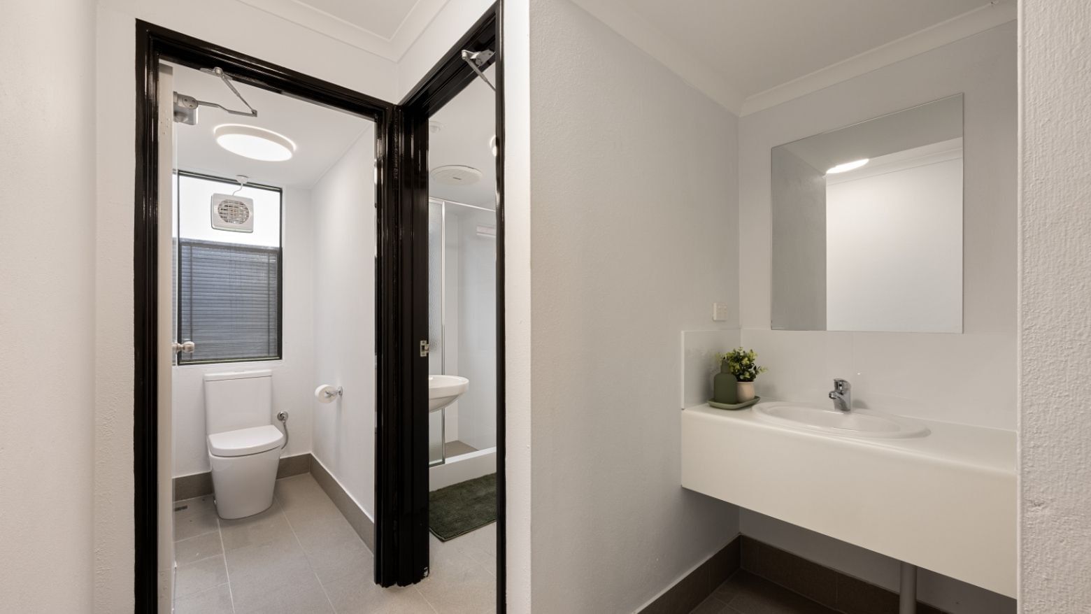 Clean white bathroom with toilet, shower, and sink at UniLodge at Curtin University - Erica Underwood House.