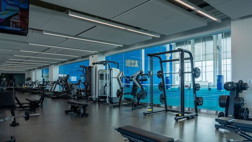 Gym interior with exercise equipment, large windows, and blue accents in 10XTO at Hotel X Toronto