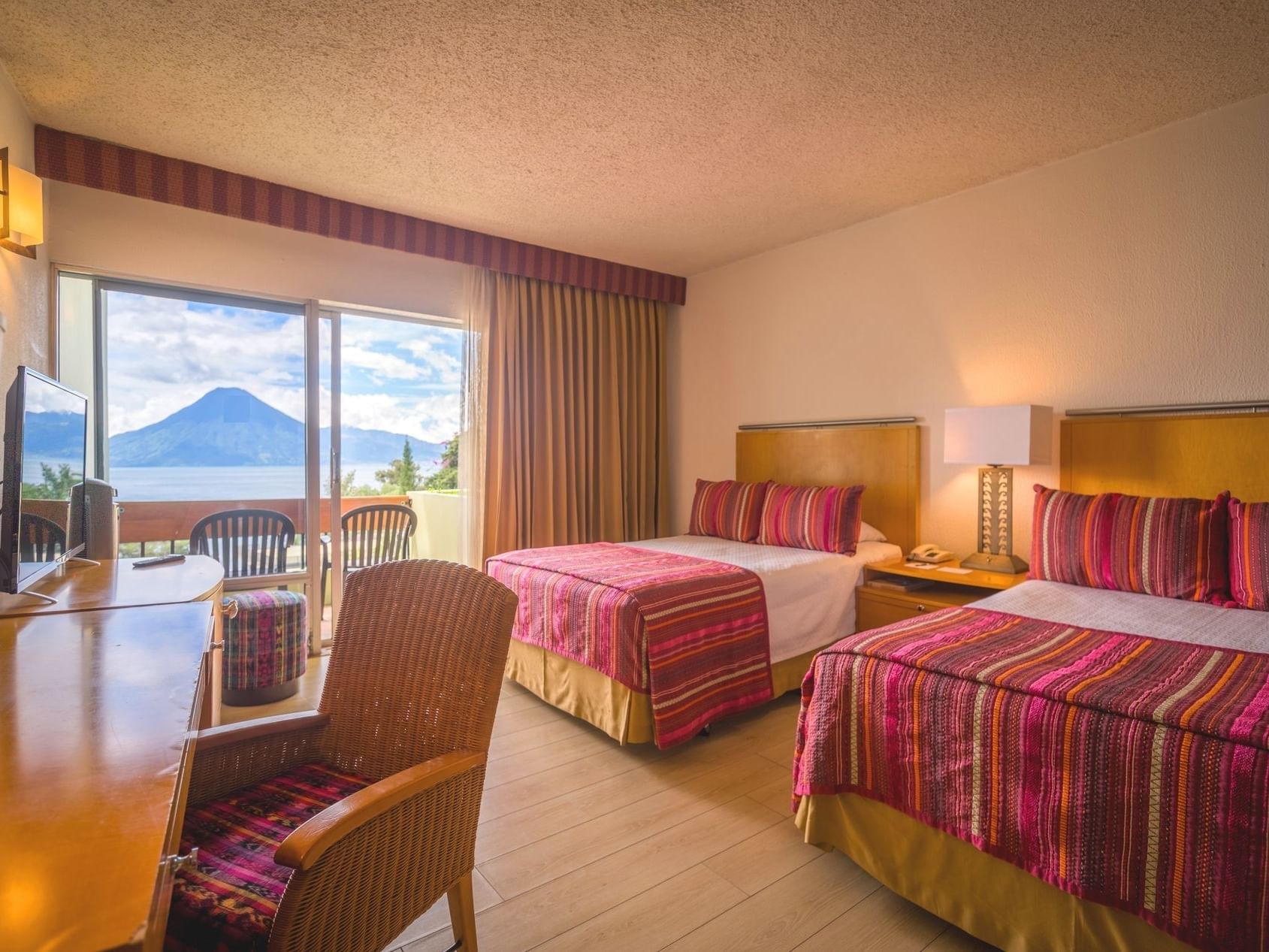 2 cozy beds, work table, and balcony with mountain view in Deluxe Room at Porta Hotel del Lago