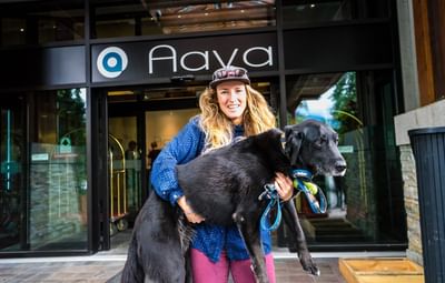 Lady posing with a dog by hotel entrance, Aava Whistler Hotel