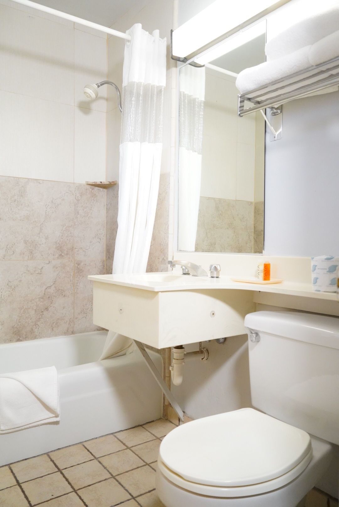 A standard hotel bathroom with a tub, toilet, sink, and mirror.
