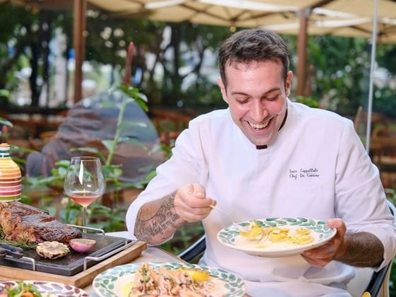 Chef Luca holding pasta with gourmet dishes and pink wine on a terrace in Opera at Park Hyatt Saigon