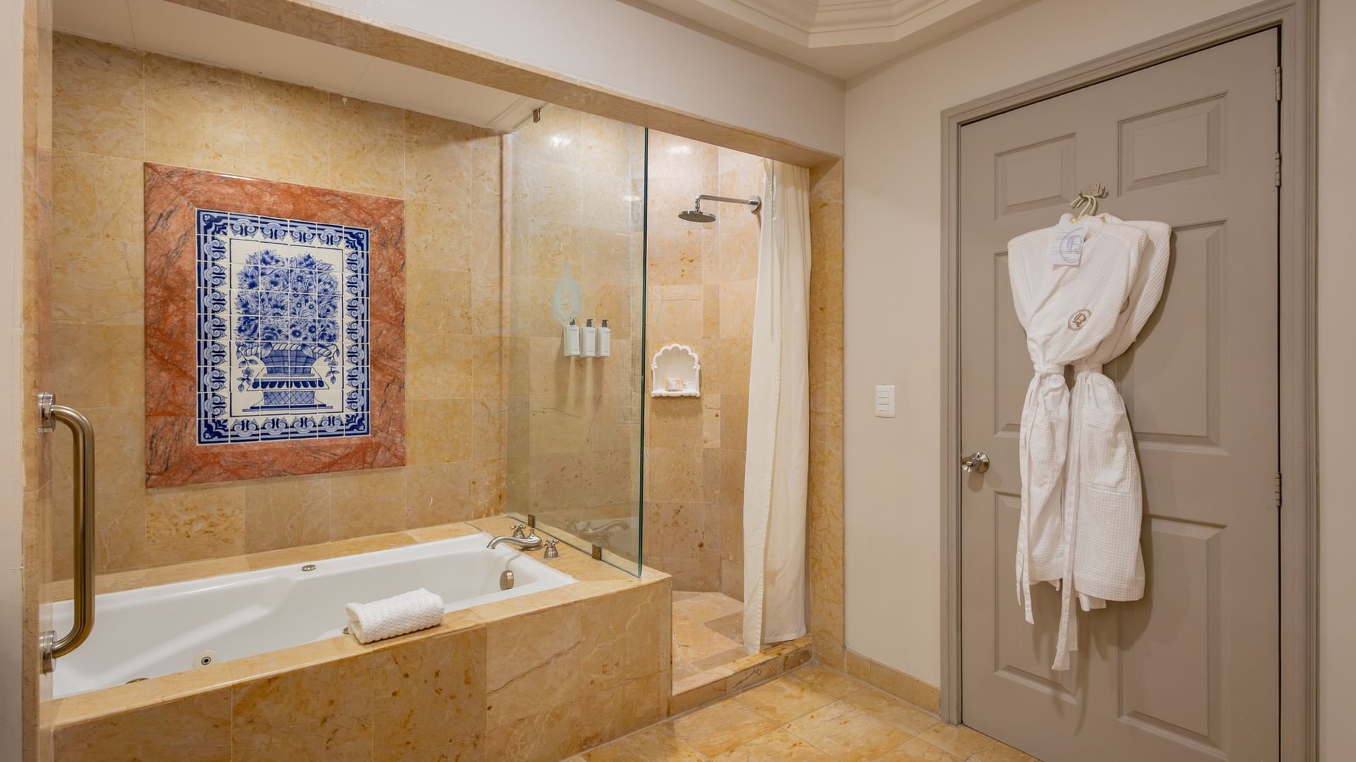 Baño de mármol con tina empotrada, regadera de cristal y decoración de talavera en Quinta Real Monterrey