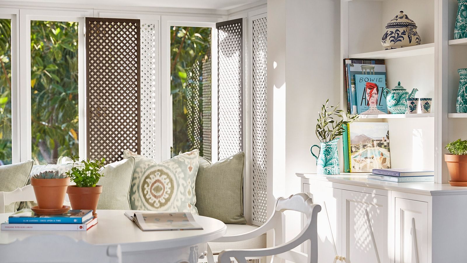 Royal Beach Suite living area with a window seat, lattice screens, & bookshelves with travel books at Marbella Club
