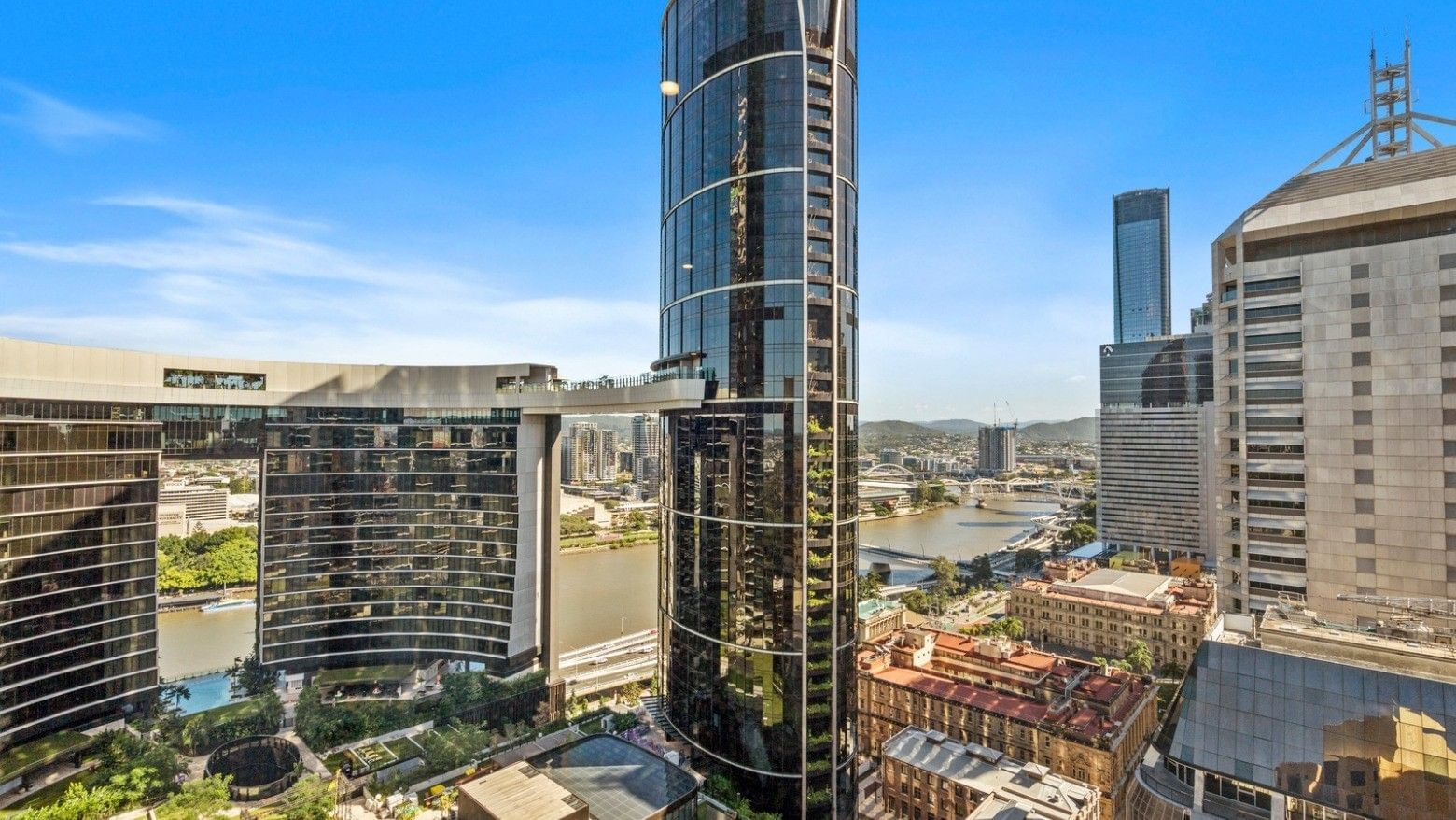 Tall modern skyscraper with surrounding buildings and a river view in an urban setting at UniLodge Brisbane City.