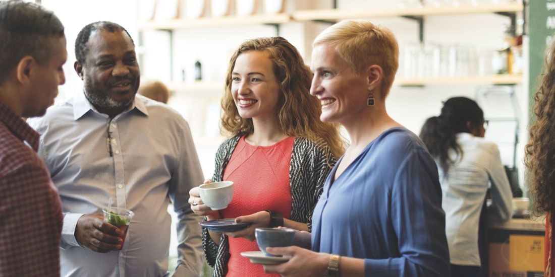 Group of friends engaging in conversation while holding cups of tea and drinks at Téséo Restaurant