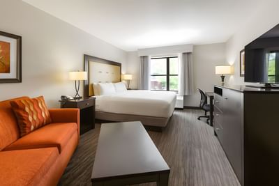 King Room with Sofa Bed featuring a king bed, orange sofa, work desk, and large window view at Branson Hillside Hotel