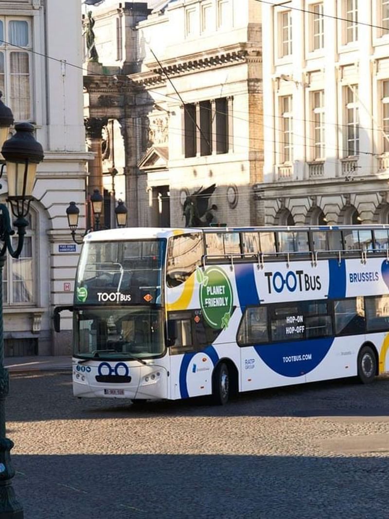 Tootbus Brussels tour bus parked on a cobblestone street near Warwick Grand Place Brussels