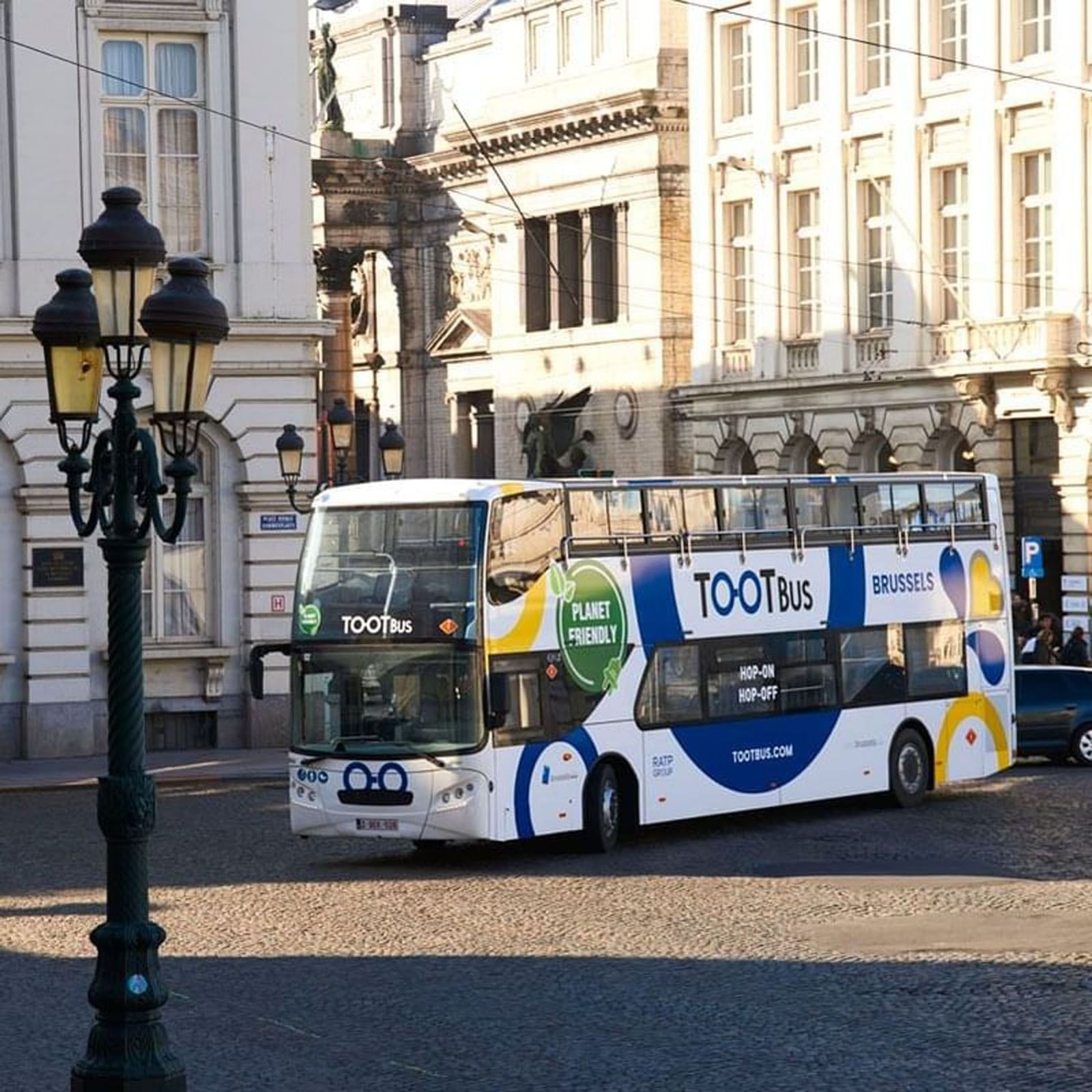 Tootbus Brussels tour bus parked on a cobblestone street near Warwick Grand Place Brussels