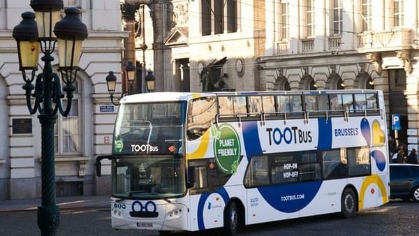 Tootbus Brussels tour bus parked on a cobblestone street near Warwick Grand Place Brussels