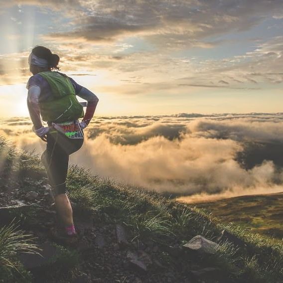 A hiker on a mountain at sunrise near Originals Hotels