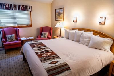 Cozy seating area and nightstand by the bed in Aspen Cabins with patterned floors at The Ranch at UCross