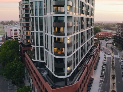 Modern urban building with balconies and cars on the road at sunset.