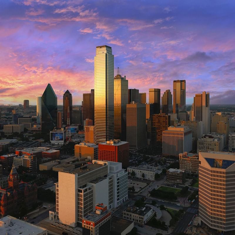 A vibrant sunset over Dallas skyline, showcasing modern skyscrapers near Warwick Hotels and Resorts