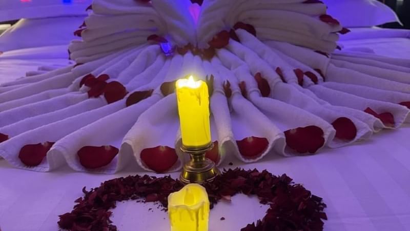 Room at Warwick Hotels and Resorts, decorated for a romantic evening with rose petals, candles, and a towel swan on the bed