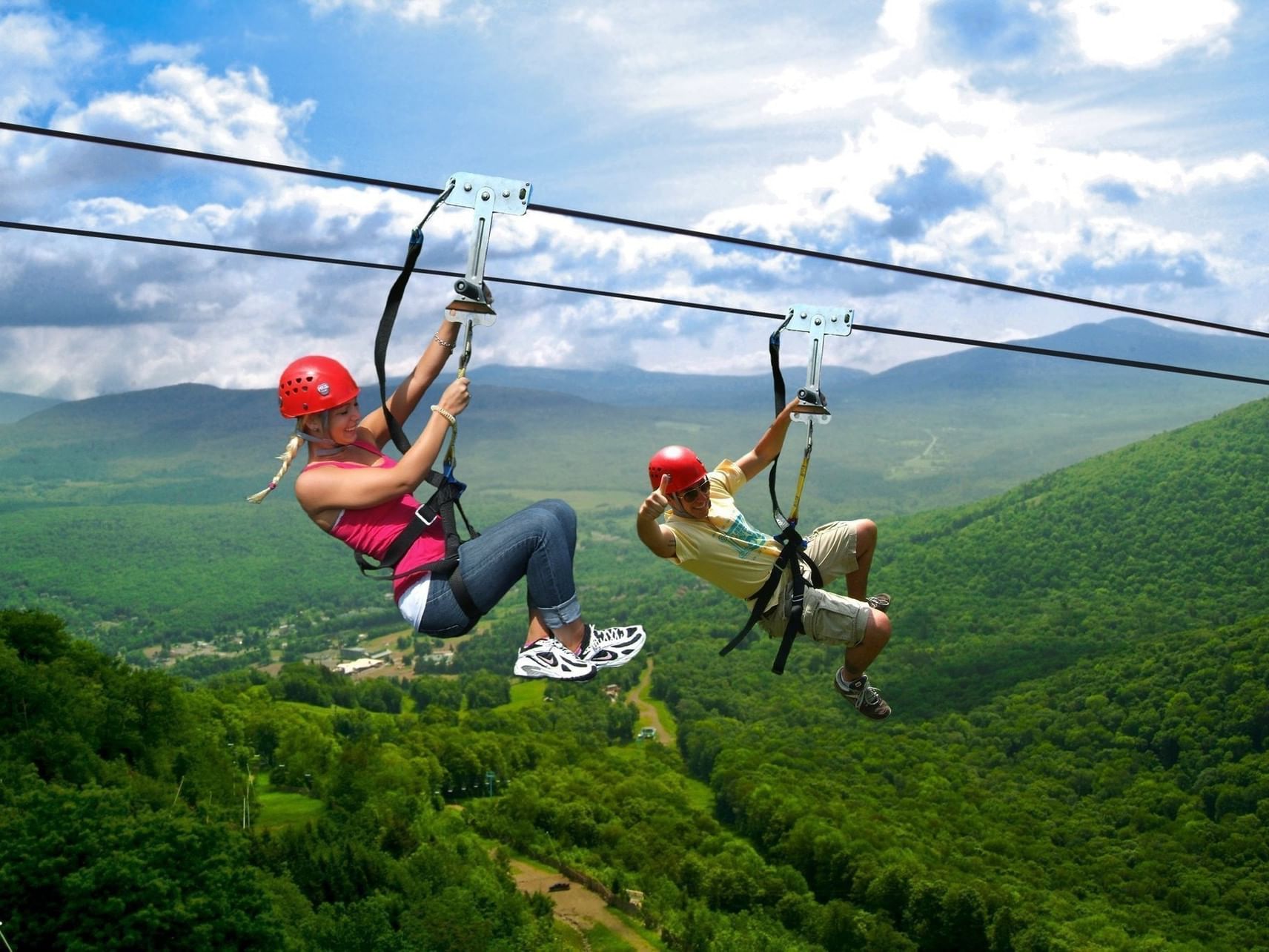 Guests on a zipline under a blue sky surrounding green hills near Morgan's Rock Reserve & Ecolodge