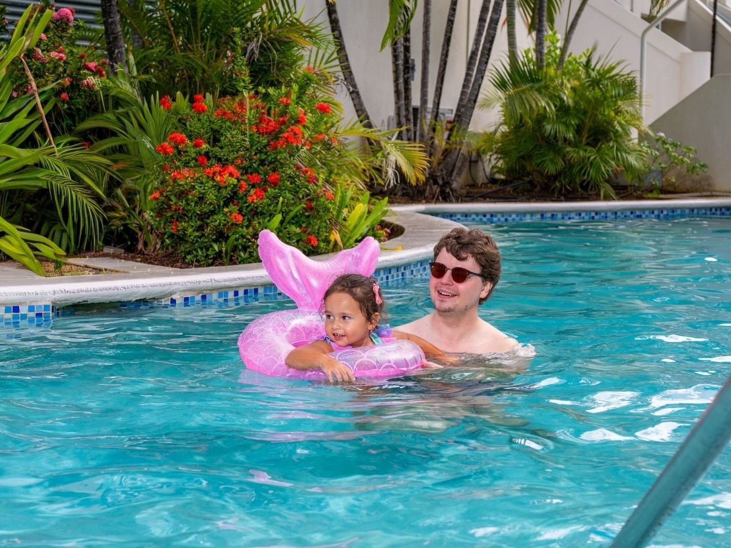 Father and daughter with float ring in pool at Savannah Beach Hotel.