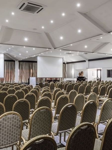 Rows of upholstered chairs by projection screens in Talanoa Hall at Warwick Fiji Resort and Spa
