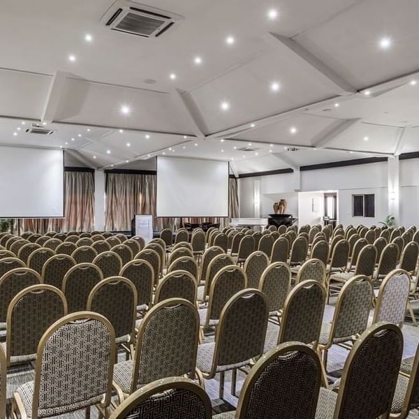Rows of upholstered chairs by projection screens in Talanoa Hall at Warwick Fiji Resort and Spa