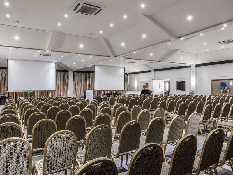 Rows of upholstered chairs by projection screens in Talanoa Hall at Warwick Fiji Resort and Spa