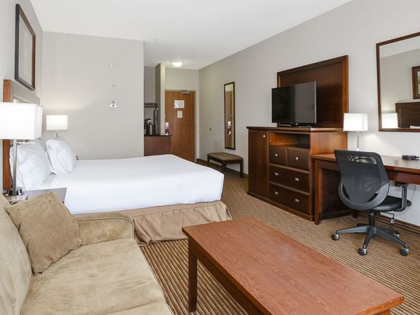 Hotel room with a king bed and a sofa bed, TV, work desk, chair, and coffee table