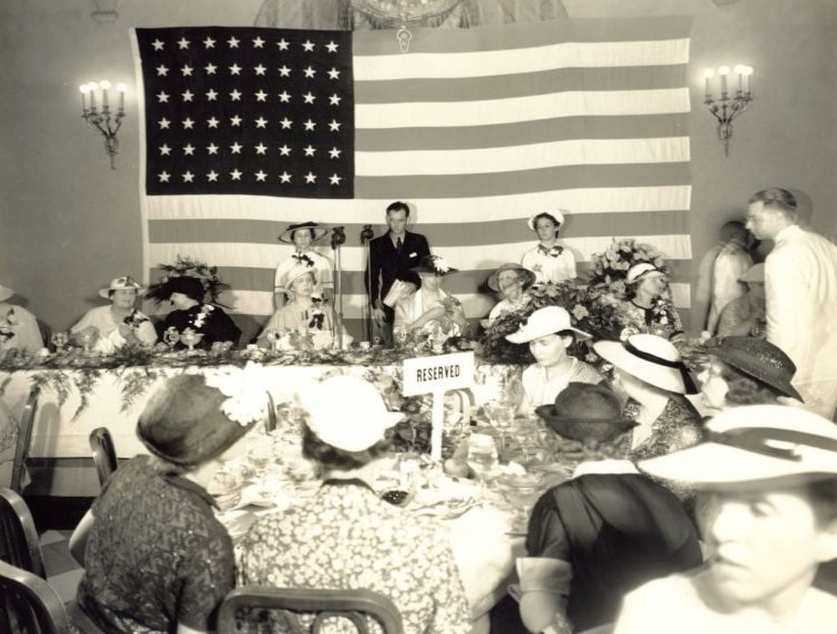 Vintage image of guests dining by floral tables under a large American flag at an event in Arlington Resort Hotel & Spa