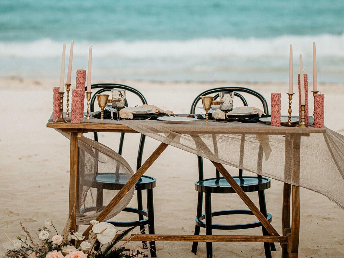 Montaje de cena a la luz de las velas en la playa en Grand Fiesta Americana