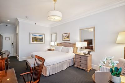 Bed with striped bench beside nightstands near wooden desk with chair in the Luxury Room at Avon Old Farms Hotel