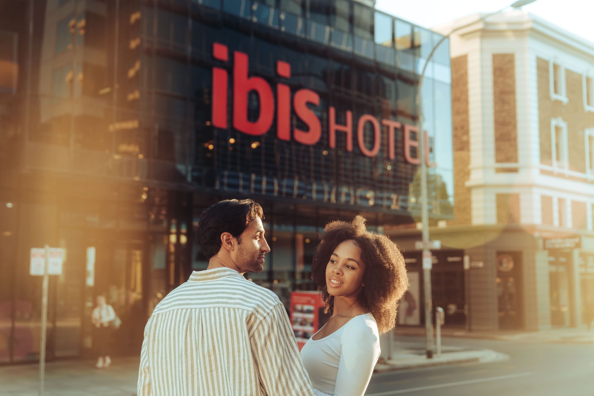 Couple smiling at each other in front of the Ibis Adelaide