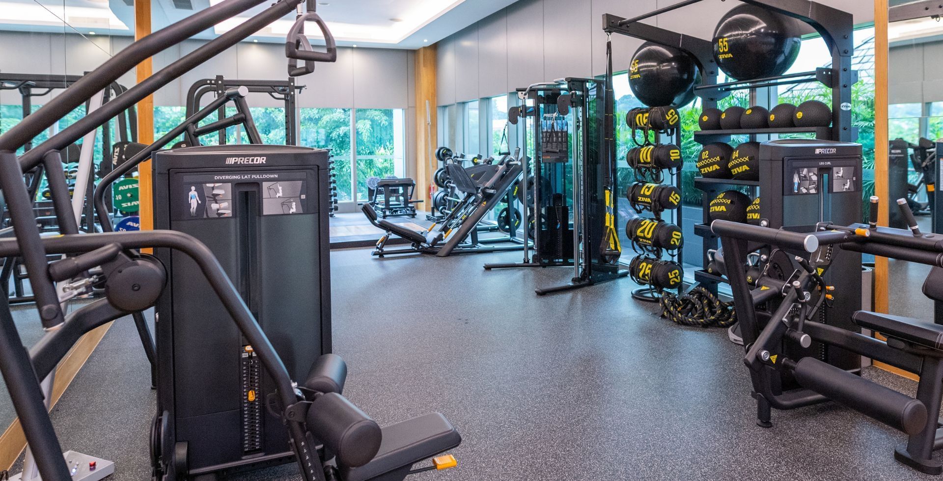 A spacious and modern hotel gym filled with various strength training equipment and natural light at Carlton Hotel Singapore