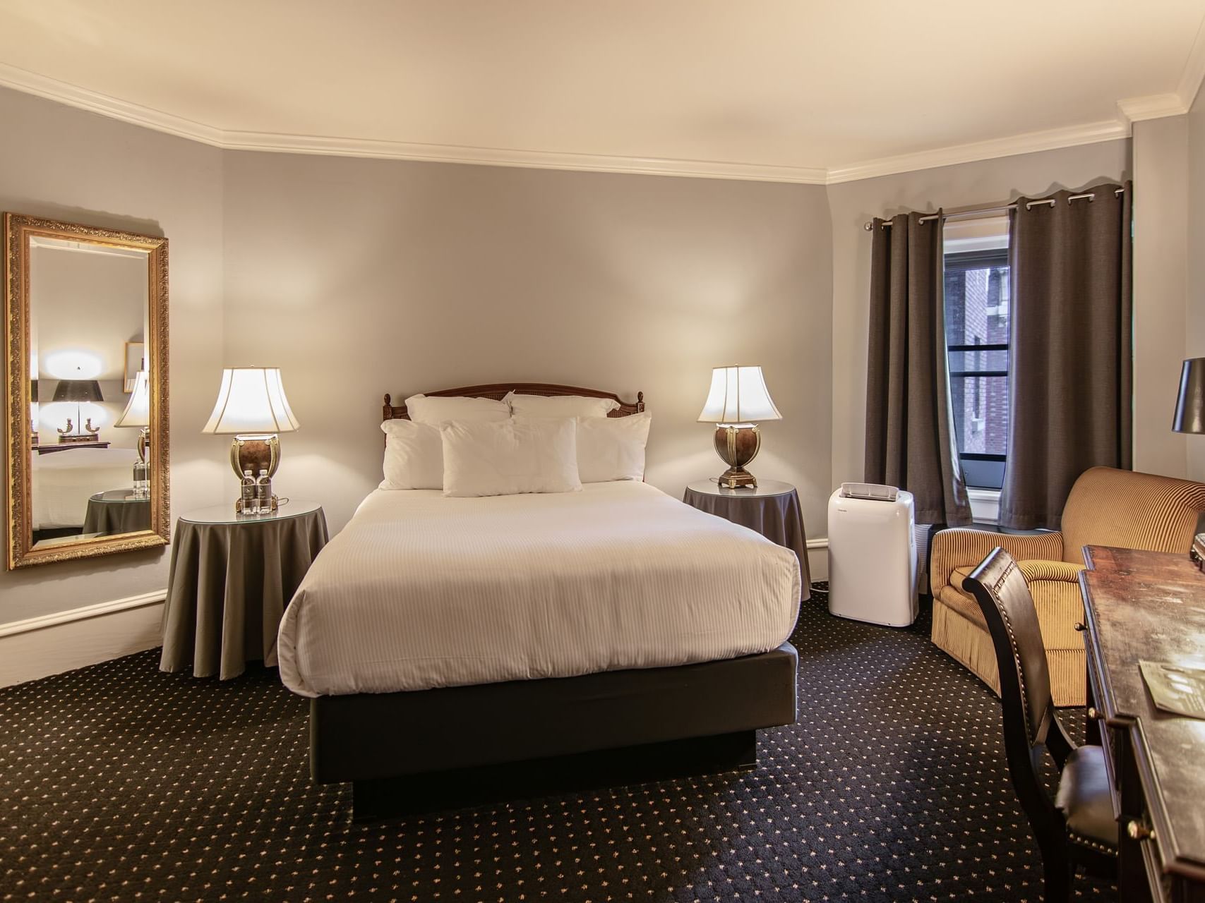 Seating area, work desk, and wall mirror by the bed in Classico Queen Room at Hotel Sorrento