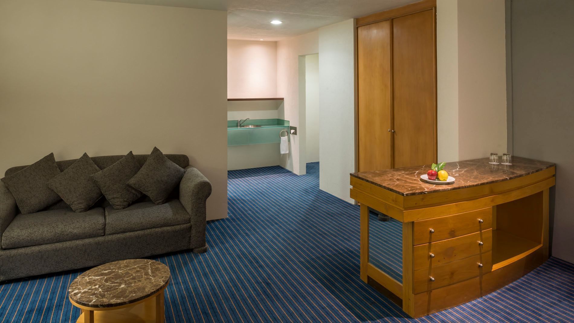 In-room kitchenette and marble counter in King Junior Suite featuring a sofa and striped flooring at Real Inn Nuevo Laredo