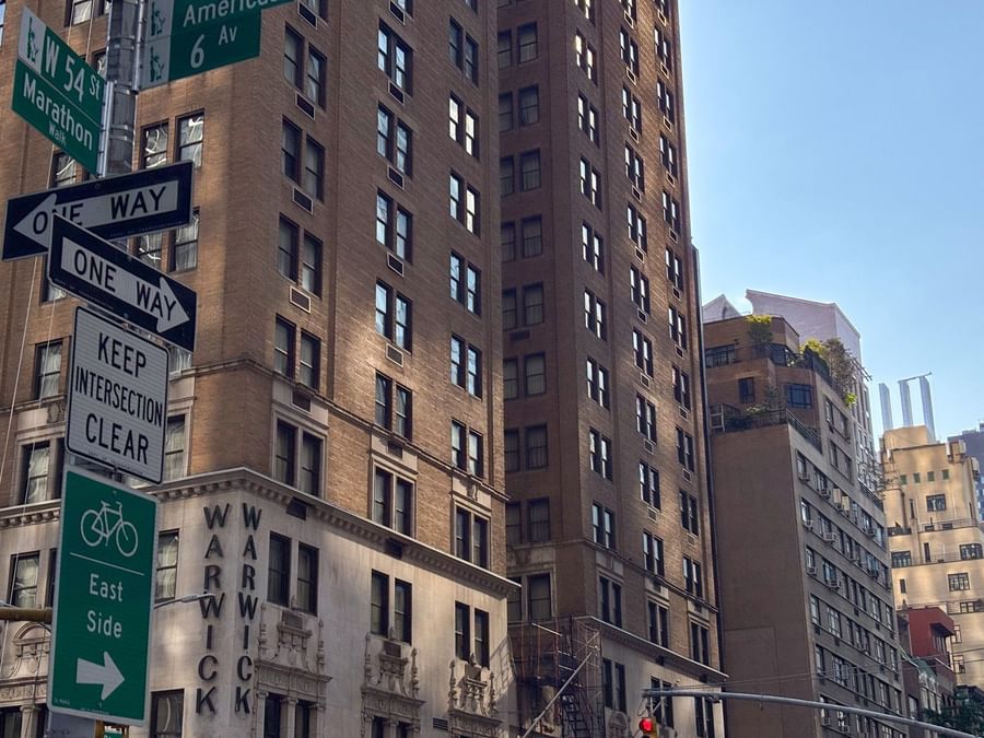 Tall Warwick New York hotel building with street signs and bicycle route sign.