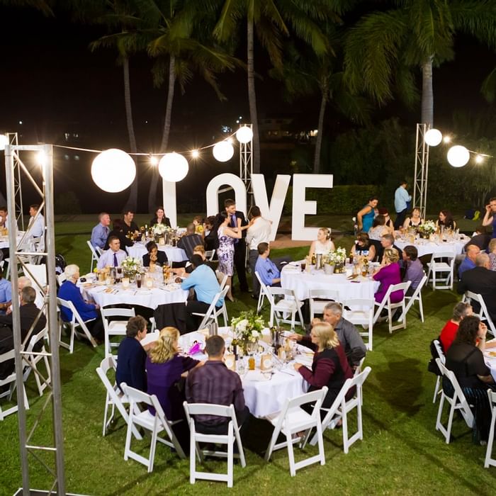 People in an outdoor night event with a love sign & hanging lights at Mercure Hotel Townsville