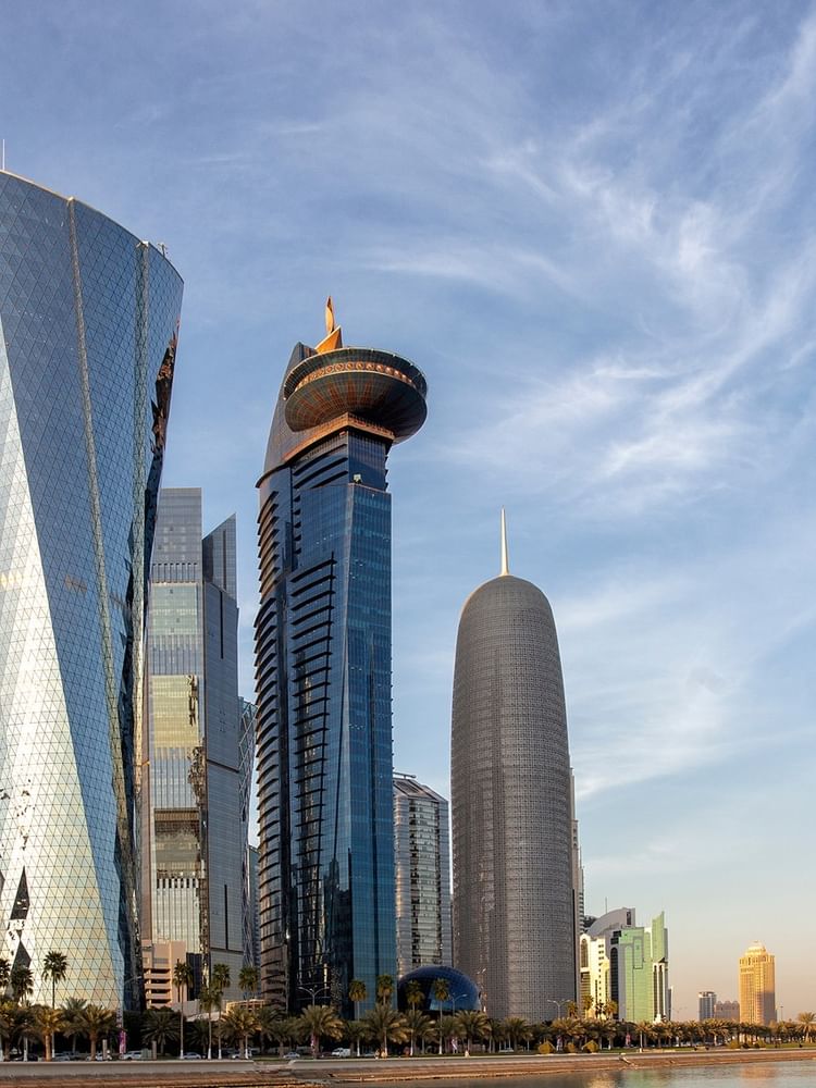 Modern skyscrapers with unique designs by the water under a clea near Warwick Hotels & Resort