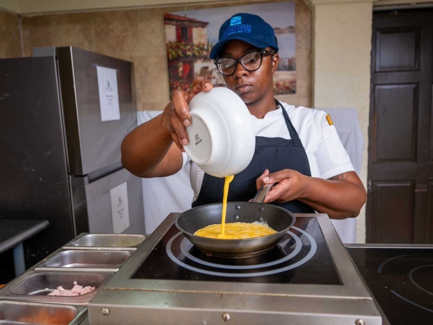 A chef pours egg mixture into a pan on a stove at Savannah Beach Hotel.