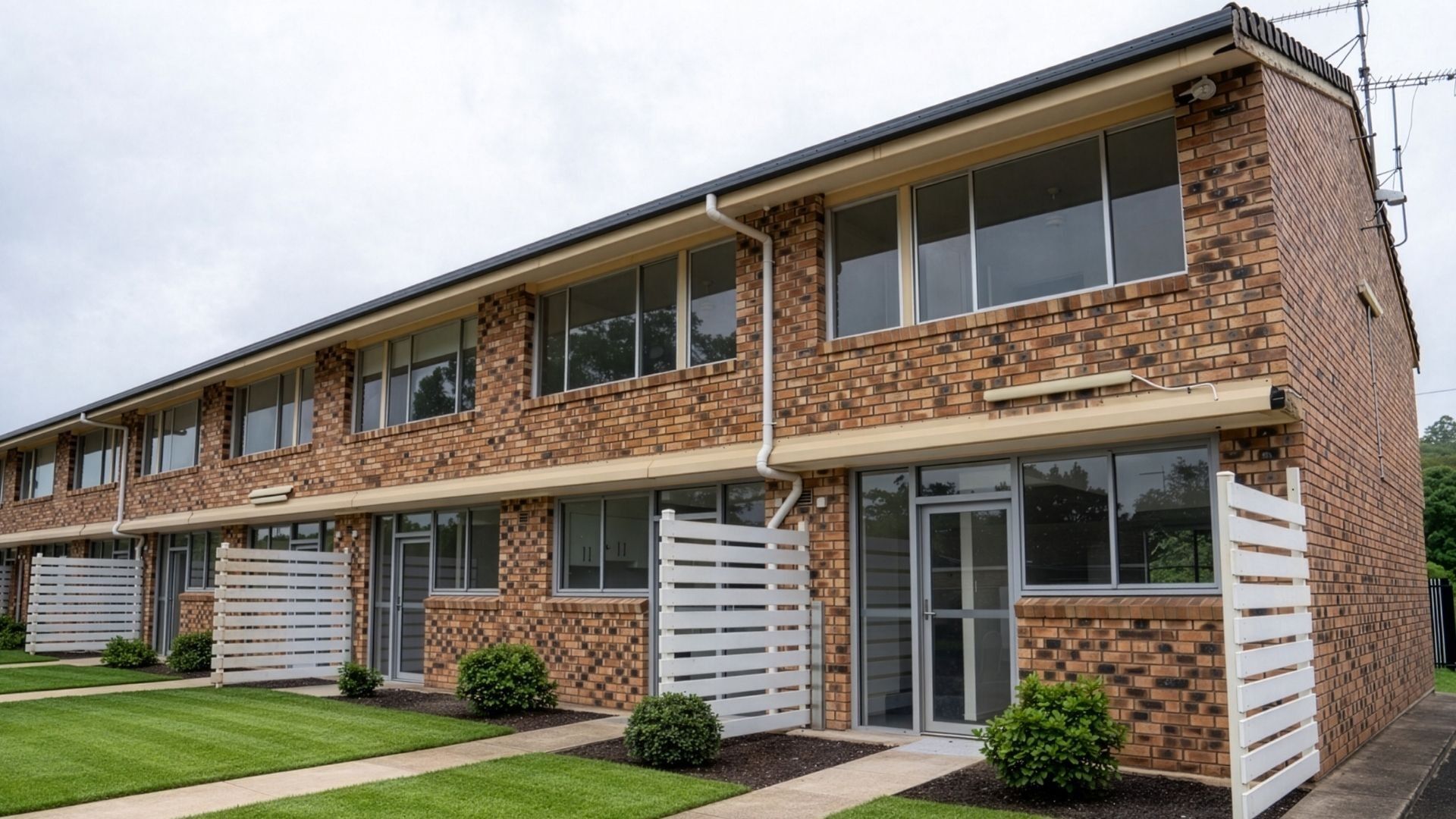 Brick building with glass windows and white fences at UniLodge SCU Lismore.