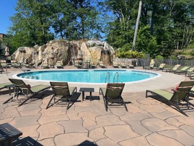 Outdoor swimming pool with lounge chairs and a rock waterfall feature at The Abbey Inn & Spa