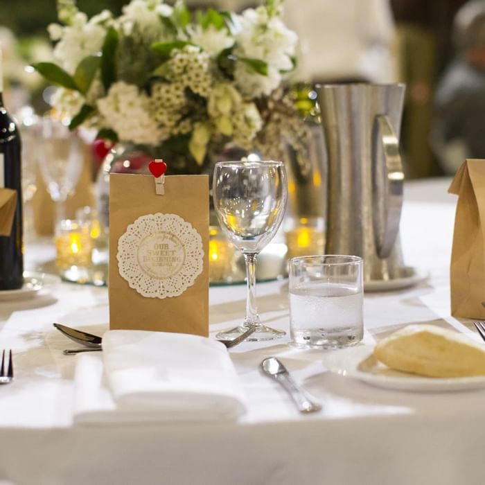 Elegant wedding dining table set featuring flower centerpieces and a wine bottle at Mercure Hotel Townsville