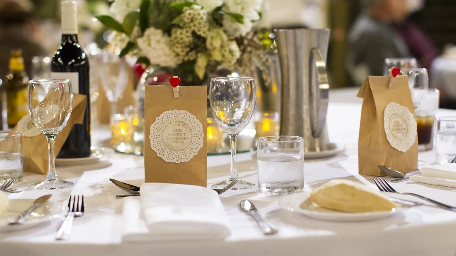 Elegant wedding dining table set featuring flower centerpieces and a wine bottle at Mercure Hotel Townsville