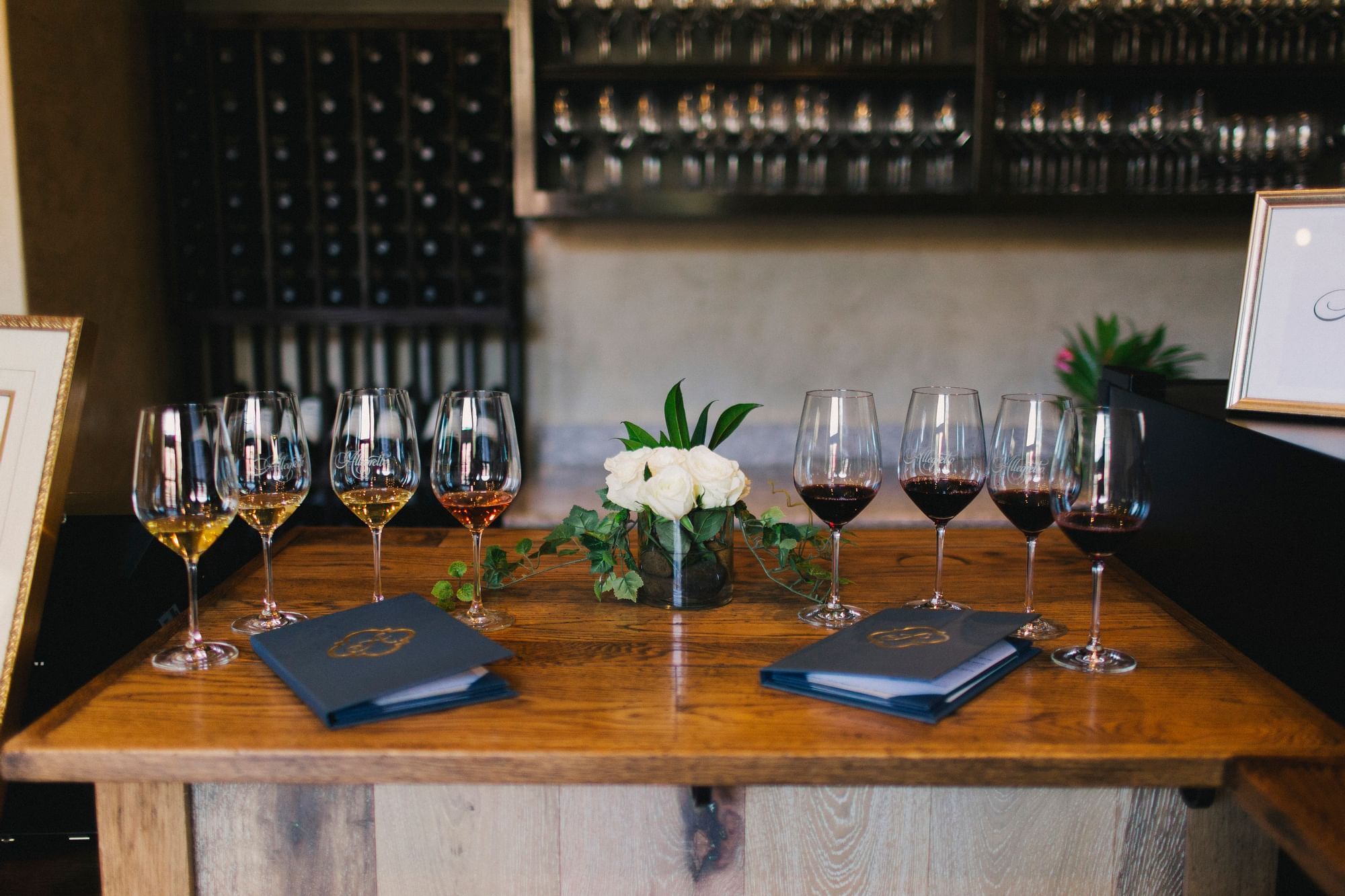 Eight glasses of wine split by a white flower arrangement