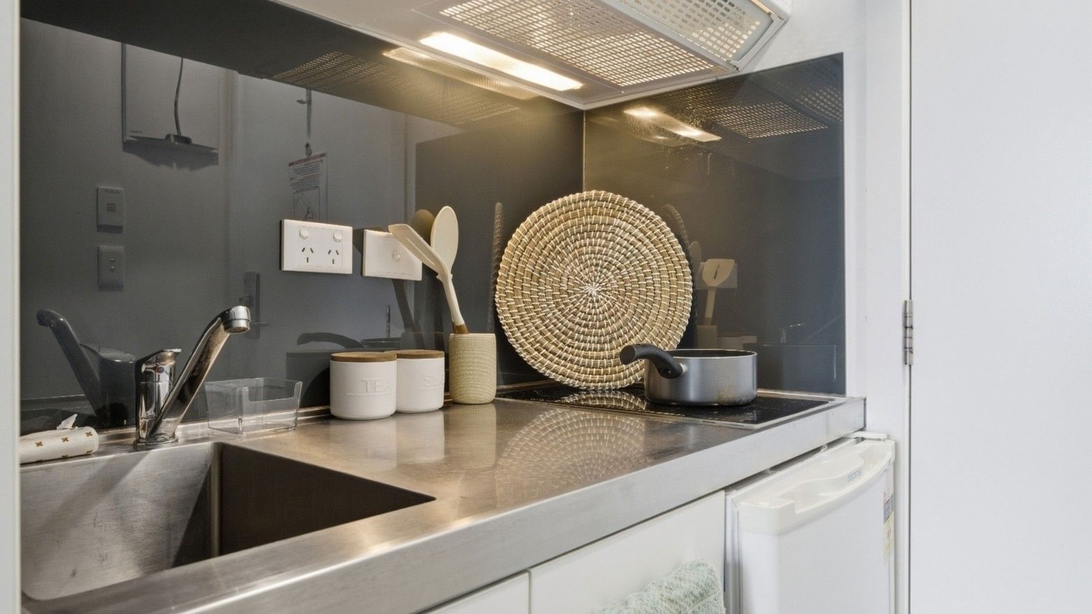 Modern kitchen with sleek sink, induction stove, and natural decor at UniLodge Auckland City.