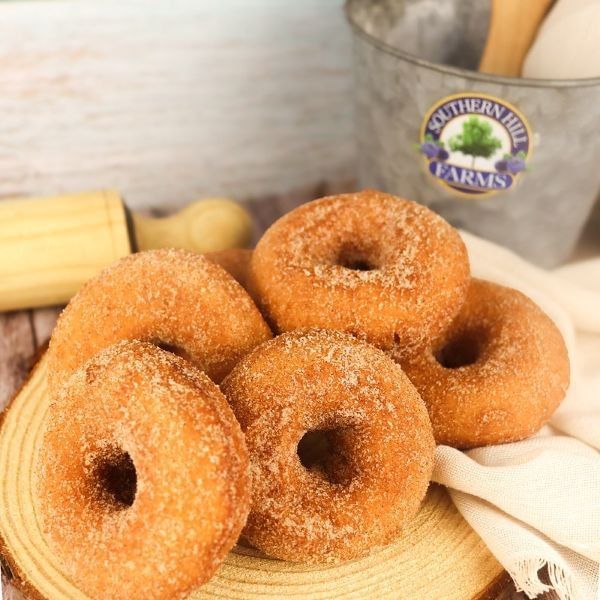 A pile of donuts rolled in cinnamon sugar next to a steel bucket with the Southern Hill Farms logo.