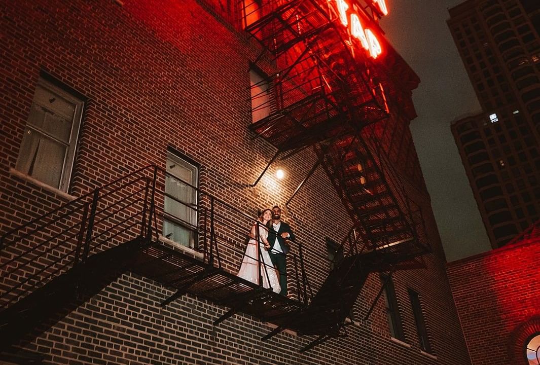 Couple standing on fire escape in front of a brick building near Warwick Allerton Chicago