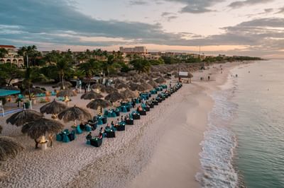 Serene beach with thatched umbrellas and tables arranged near Passions on the Beach