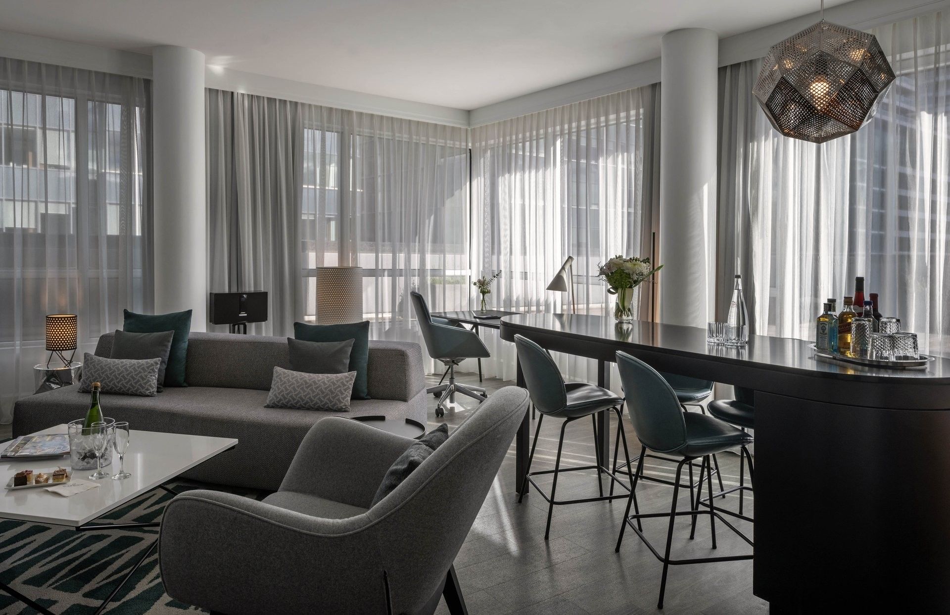 Modern suite with grey sofa & bar seating & geometric lamp at Warwick Le Crystal Montreal