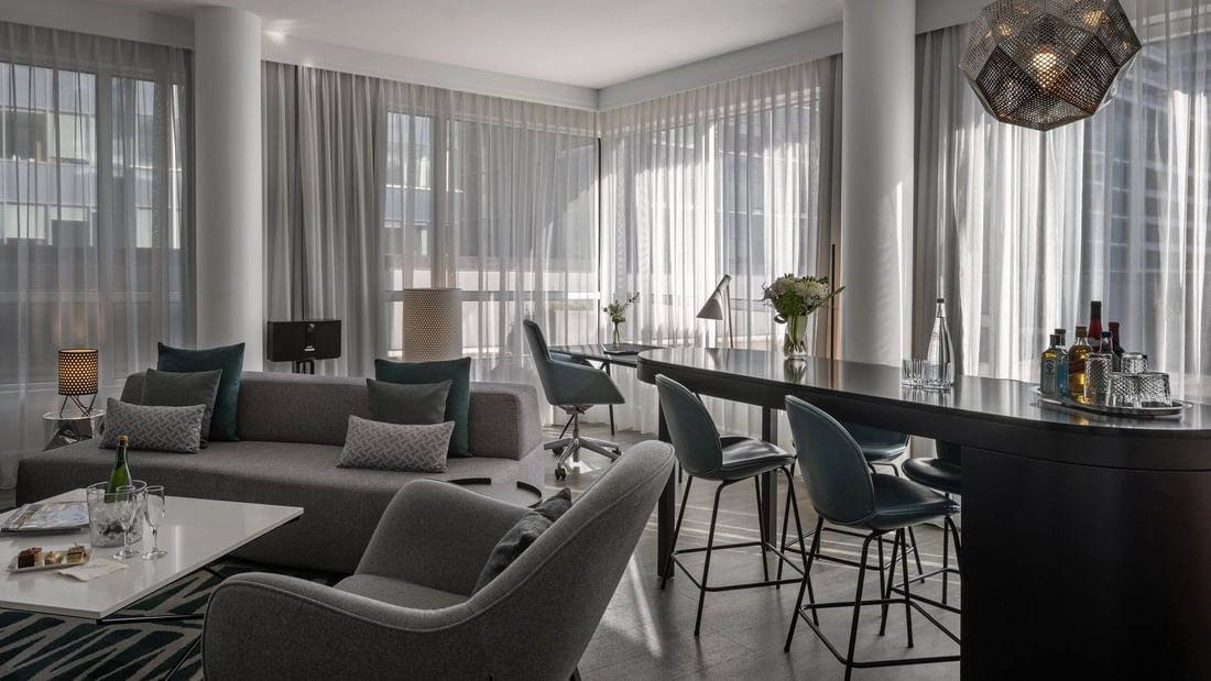Penthouse René-Lévesque living area with plush sofa and bar counter near window at Warwick Le Crystal Montreal
