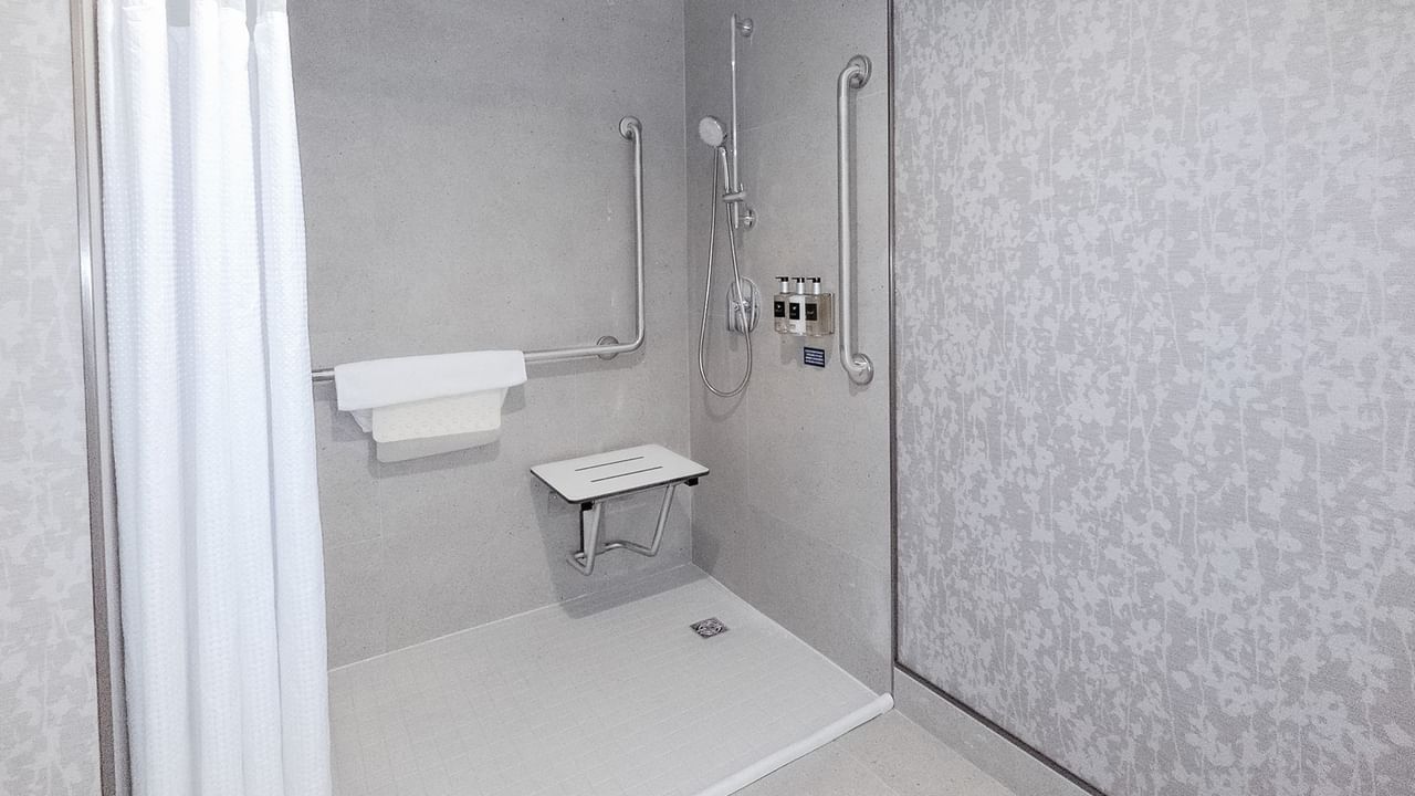 Accessible hotel washroom with roll-in shower with bench