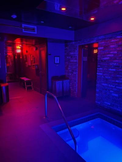 Dimly lit corridor with red and blue lights, featuring a small hot tub with stairs at The Gaythering